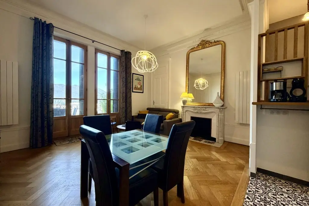 salon avec fauteuil, canapé, table basse, cheminée, miroir et accès balcon