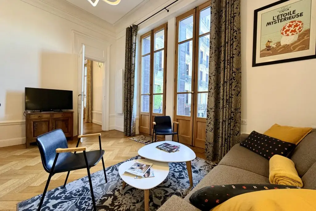 salon avec fauteuil, canapé, table basse, cheminée, miroir et accès balcon