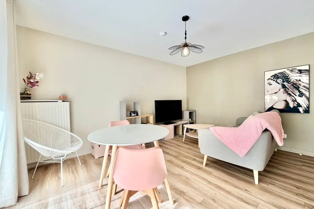 vue de la salle à mager avec table et 4 chaises et salon avec tv et canapé