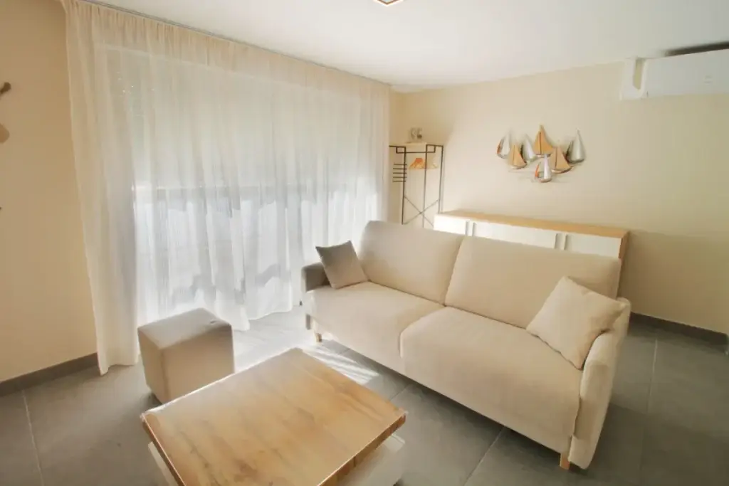 salon avec canapé, table basse et pouf avec accès balcon